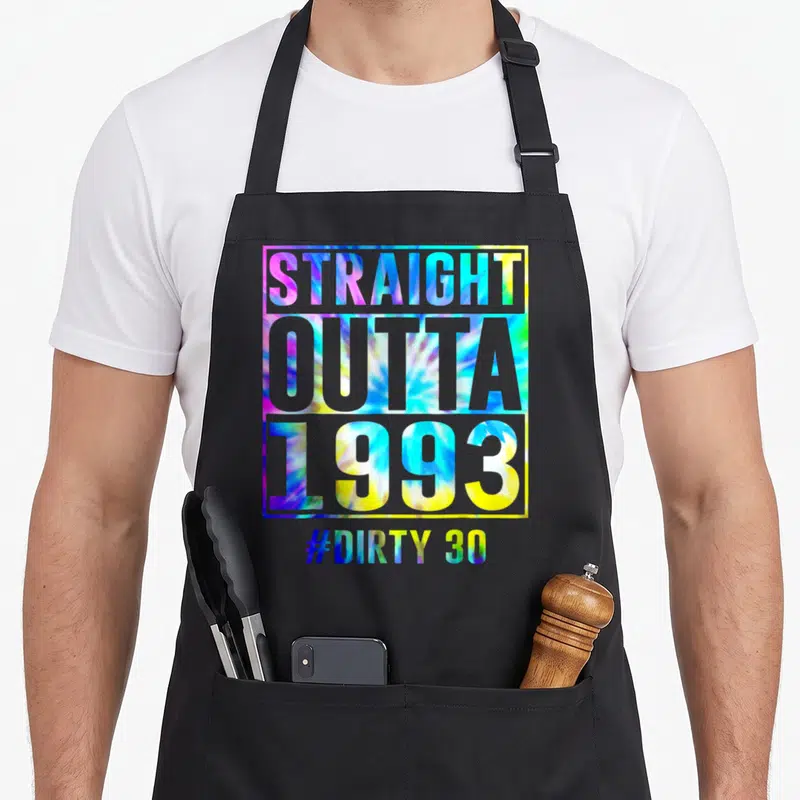 Outta thirty funny dirty aprons - Stacked tie-dye typography reading STRAIGHT OUTTA 1993 and #DIRTY 30 inside a square — shown on a black cotton canvas apron against a white background