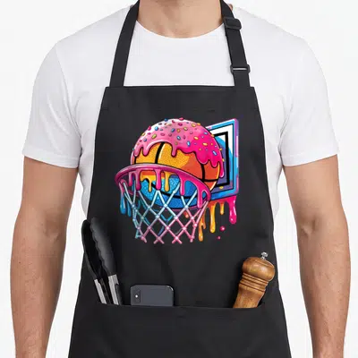 Basketball player ice cream apron - Cartoon basketball covered in pink frosting and sprinkles falling through a pink — shown on a black cotton canvas apron against a white background