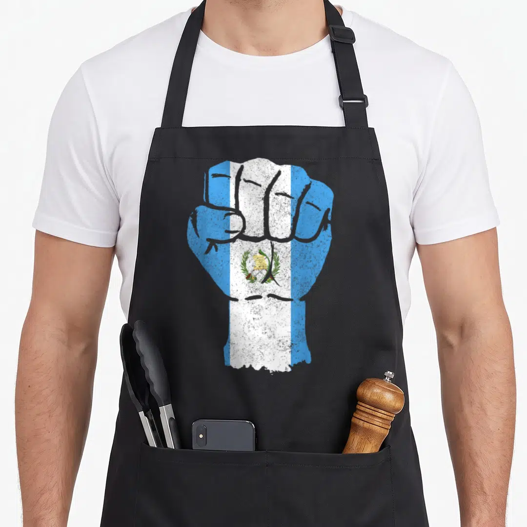 Pride chapina guatemalan aprons - Clenched fist filled with blue and white Guatemalan flag colors in a distressed print — shown on a black cotton canvas apron against a white background