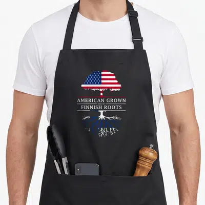 Grown finnish apron - Tree with US flag canopy and Finnish flag roots separated by text — shown on a black cotton canvas apron against a white background