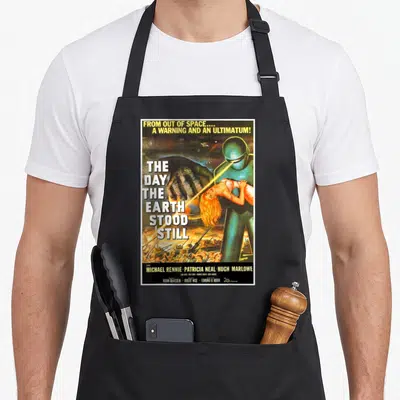 Sci halloween apron - Retro movie poster for The Day the Earth Stood Still showing a giant alien and woman in yellow — shown on a black cotton canvas apron against a white background