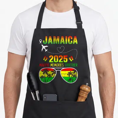 Jamaica family memory apron - Retro 2025 Jamaica apron with sunglasses, airplane, and making memories together text — shown on a black cotton canvas apron against a white background