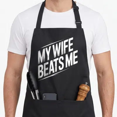 Beat husband wife aprons - White stacked text reading MY WIFE BEATS ME tilted diagonally upwards — shown on a black cotton canvas apron against a white background