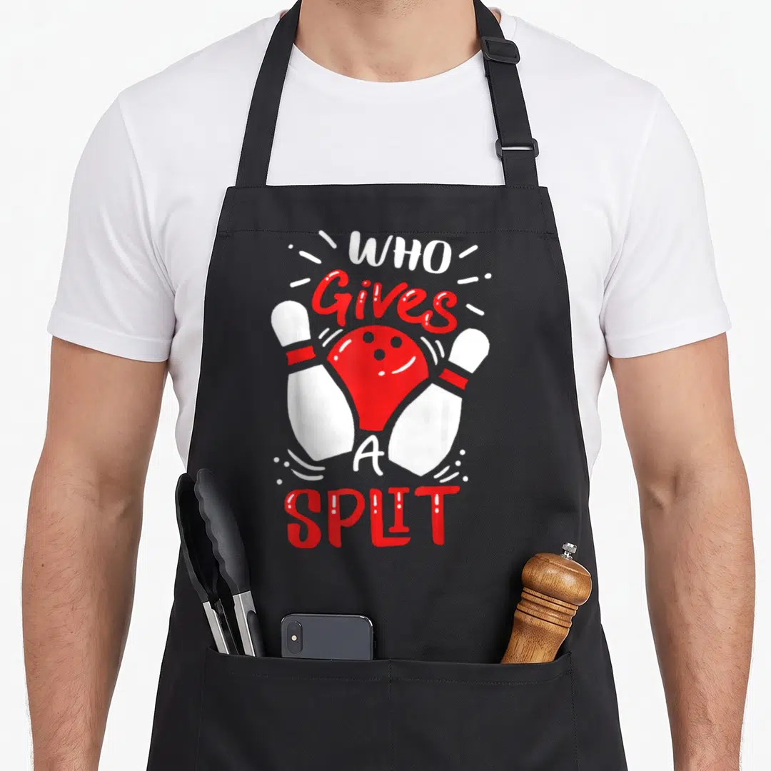 Bowler pins for aprons - Red bowling ball between two white pins with Who Gives A Split text — shown on a black cotton canvas apron against a white background