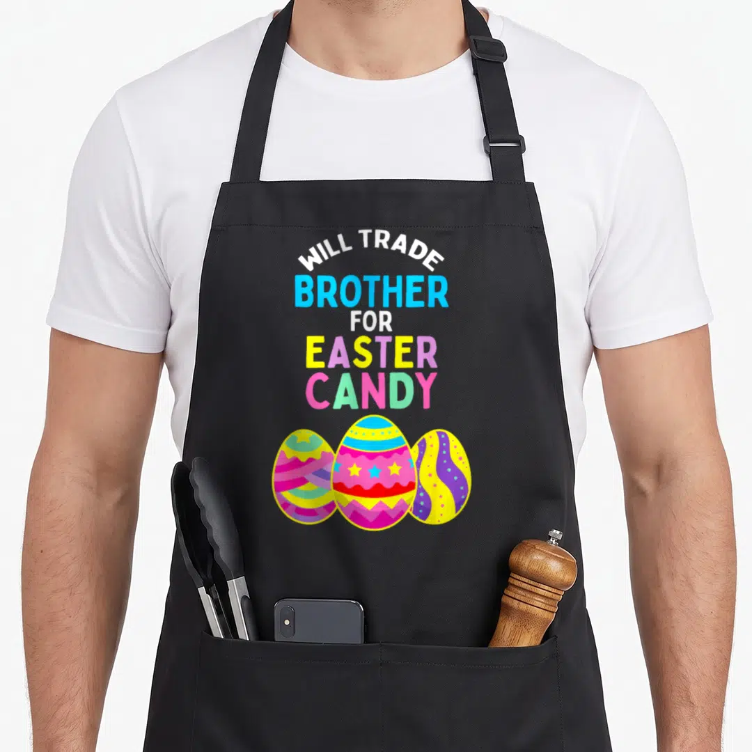 Trade easter egg apron - Stacked Will Trade Brother for Easter Candy text above three colorful cartoon Easter eggs — shown on a black cotton canvas apron against a white background