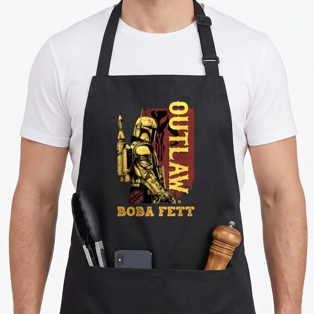 Galactic boba apron - Retro character in yellow armor with vertical OUTLAW text and maroon background — shown on a black cotton canvas apron against a white background