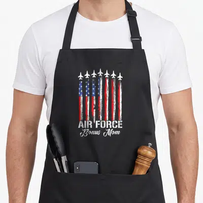 Air family aprons - Seven white jets trailing distressed red white and blue flag stripes above bold text — shown on a black cotton canvas apron against a white background
