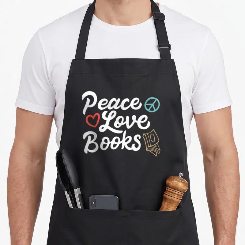 Peace geeky aprons - Stacked text Peace Love Books with peace sign heart and book stack icon — shown on a black cotton canvas apron against a white background