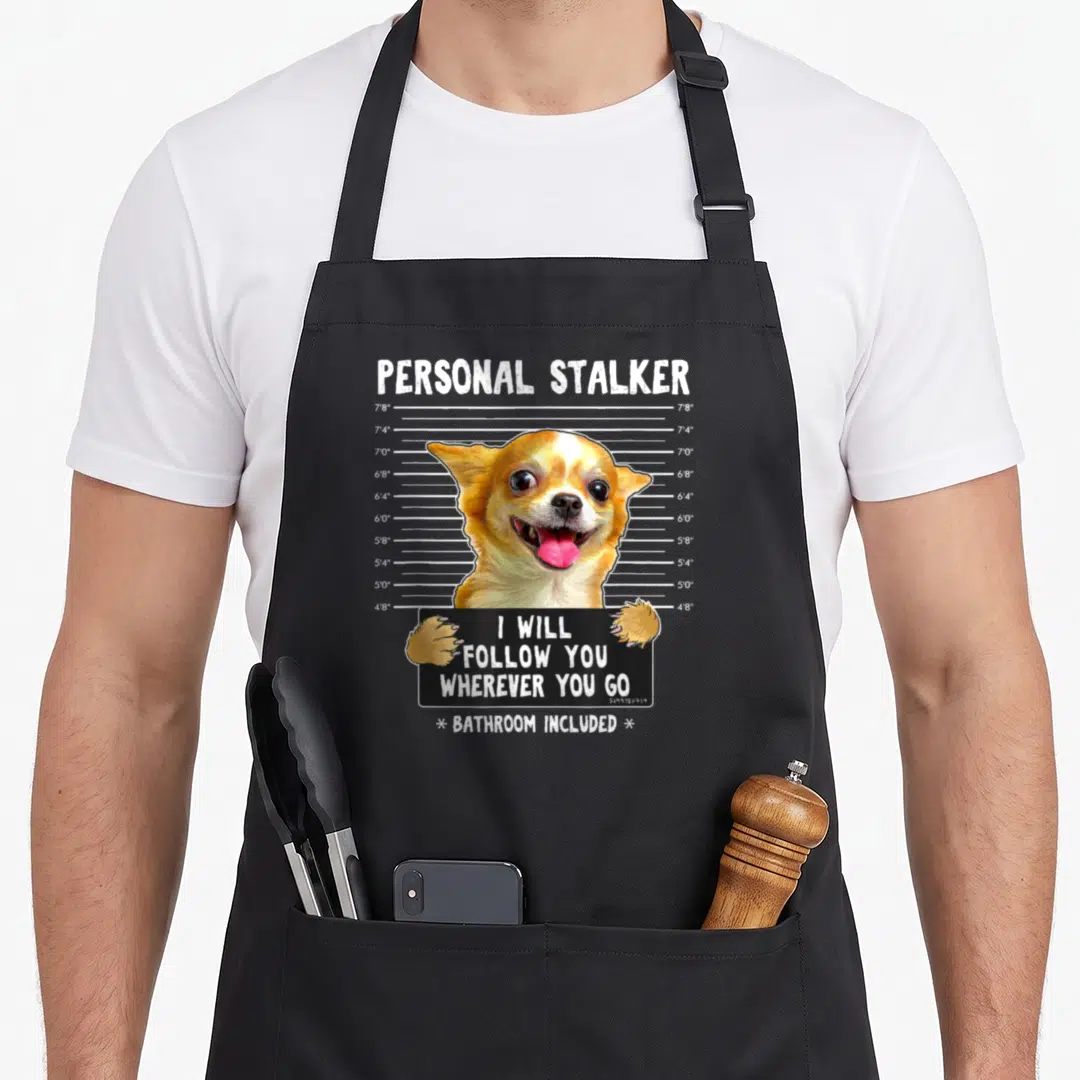 Follow personal apron - Chihuahua mugshot holding black sign with personal stalker text and height chart measurements — shown on a black cotton canvas apron against a white background