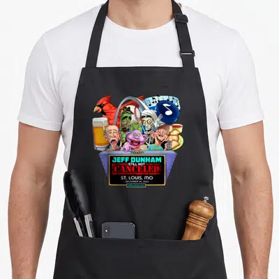 Louis hollywood apron - Jeff Dunham puppets and St Louis MO 2023 text with red blue cyan yellow white cartoon art — shown on a black cotton canvas apron against a white background