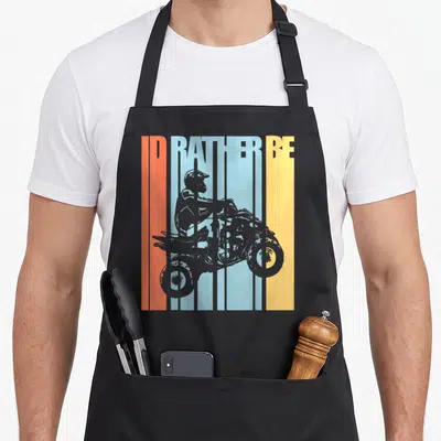 Riding bike apron - ID RATHER BE text over grey ATV rider on orange blue yellow grey stripes — shown on a black cotton canvas apron against a white background