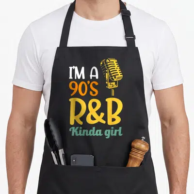 90s kinda r aprons - Stacked I'M A 90'S R&B Kinda girl text in white orange yellow green with yellow vintage microphone — shown on a black cotton canvas apron against a white background