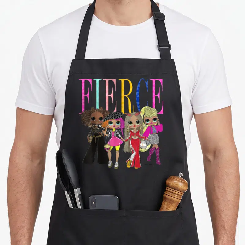 Lol shot apron - FIERCE text behind four standing dolls in pink yellow blue and black cartoon art — shown on a black cotton canvas apron against a white background