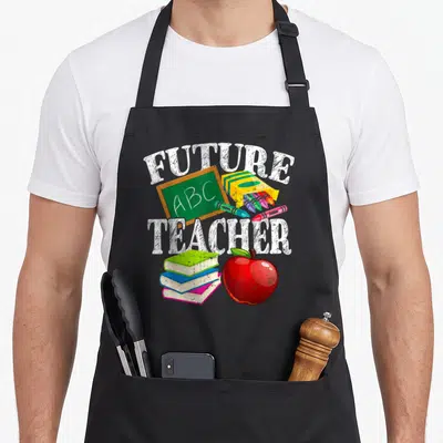 Canyon teacher apron - FUTURE ABC TEACHER text with chalkboard, crayons, books, and red apple — shown on a black cotton canvas apron against a white background