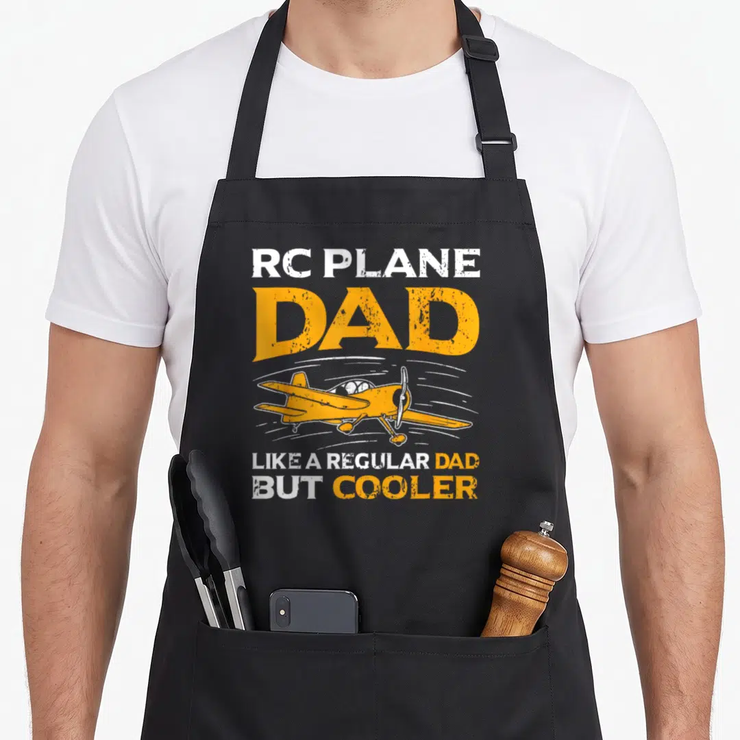 Pilot model airplane apron - Orange and white distressed text RC Plane Dad surrounding a model airplane graphic — shown on a black cotton canvas apron against a white background