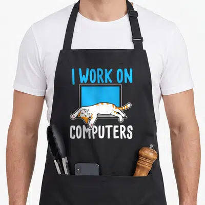 Computer kitty cat apron - Cartoon cat lying across blue monitor with I Work On Computers text — shown on a black cotton canvas apron against a white background