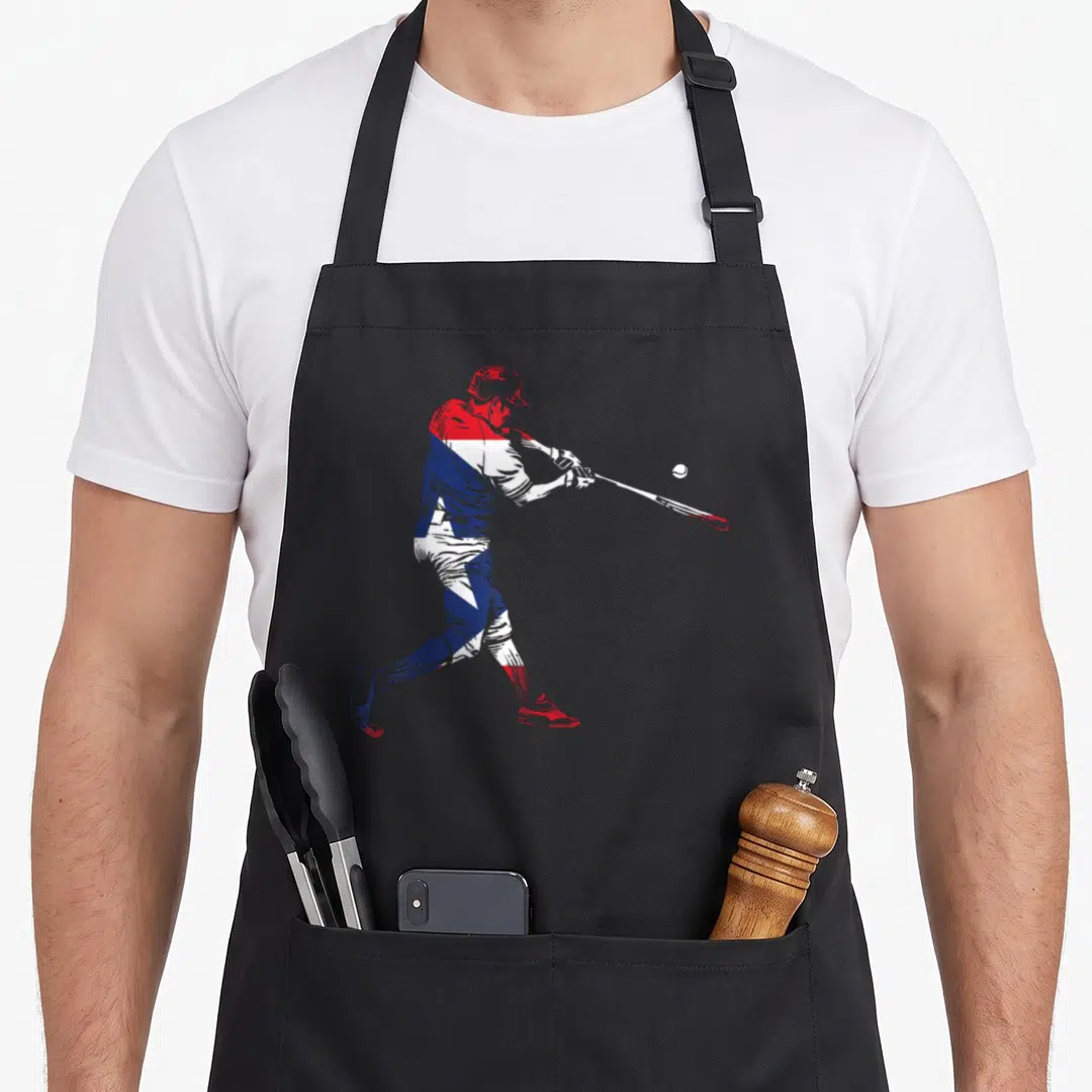 Puerto kitchen island apron - Baseball player swinging bat in red white and blue silhouette — shown on a black cotton canvas apron against a white background