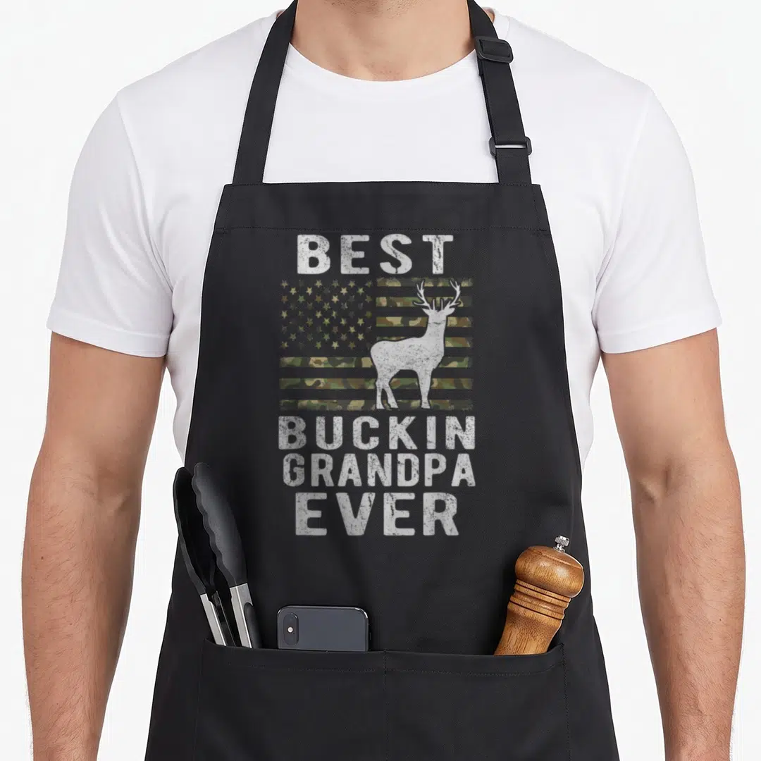 Bucking grandpa apron - Camo US flag with white deer silhouette and distressed text Best Buckin Grandpa Ever — shown on a black cotton canvas apron against a white background