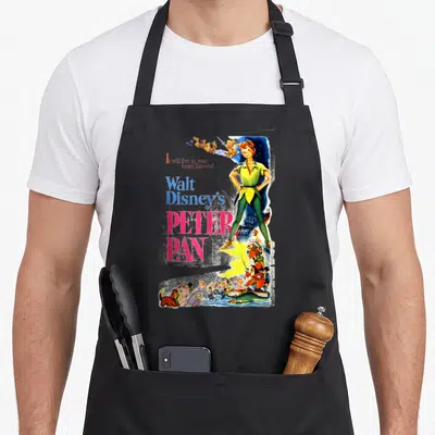 Peter cartoon apron - Vintage Peter Pan poster art with stacked text and colorful character figures — shown on a black cotton canvas apron against a white background