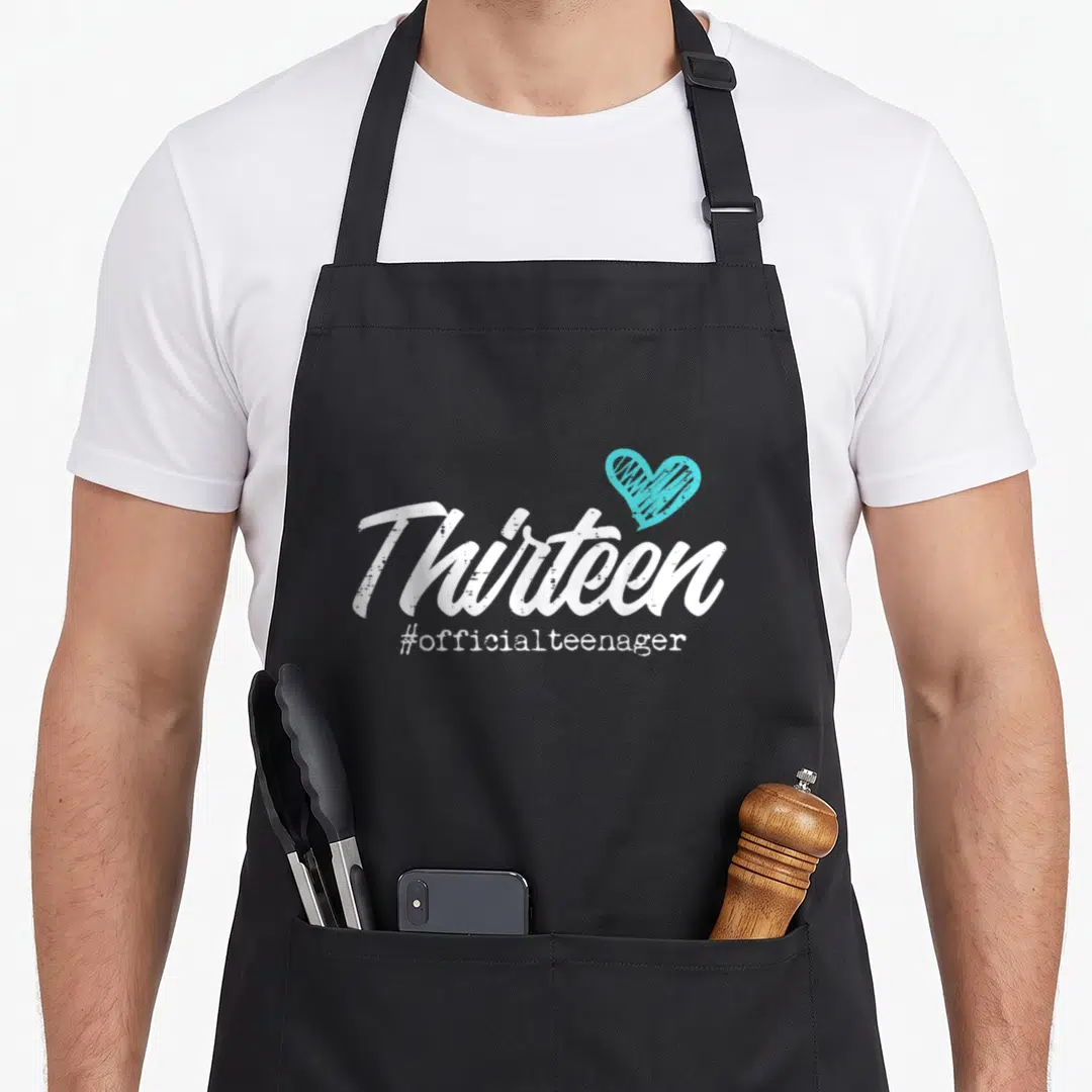Thirteen 13th birthday apron - White Thirteen script with teal heart and #officialteenager text below — shown on a black cotton canvas apron against a white background