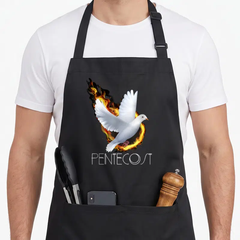Pentecost flame apron - Realistic white dove flying in orange and yellow fire circle above PENTECOST text — shown on a black cotton canvas apron against a white background