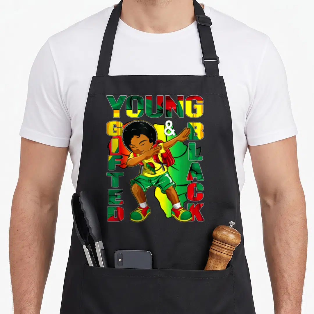 History gifted apron - Cartoon boy dabbing surrounded by YOUNG GIFTED & BLACK text in red green and yellow patterns — shown on a black cotton canvas apron against a white background