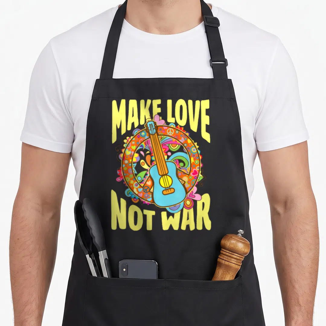 War 60s apron - Blue guitar over orange peace sign circle with yellow MAKE LOVE NOT WAR text — shown on a black cotton canvas apron against a white background
