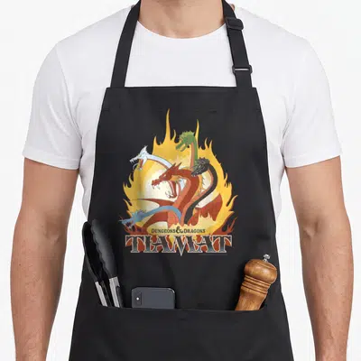 Tiamat flame apron - Five headed dragon in red yellow blue green black on large flame with stacked Dungeons Dragons — shown on a black cotton canvas apron against a white background