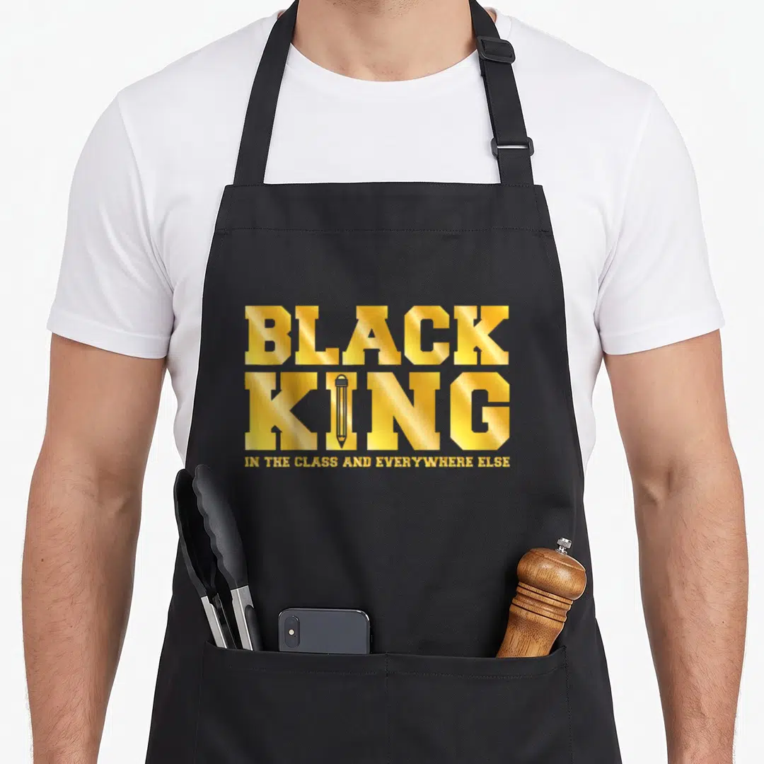 Class king apron - Gold text reading BLACK KING IN THE CLASS AND EVERYWHERE ELSE with a pencil replacing the I — shown on a black cotton canvas apron against a white background