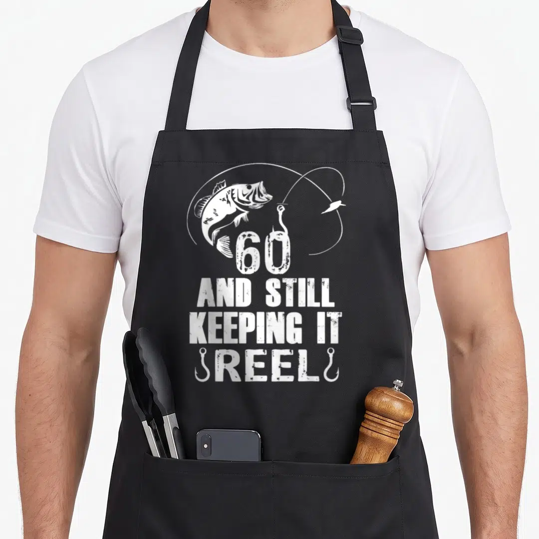 Keeping 60th birthday apron - White fish jumping above 60 text and fishing hooks on black apron — shown on a black cotton canvas apron against a white background