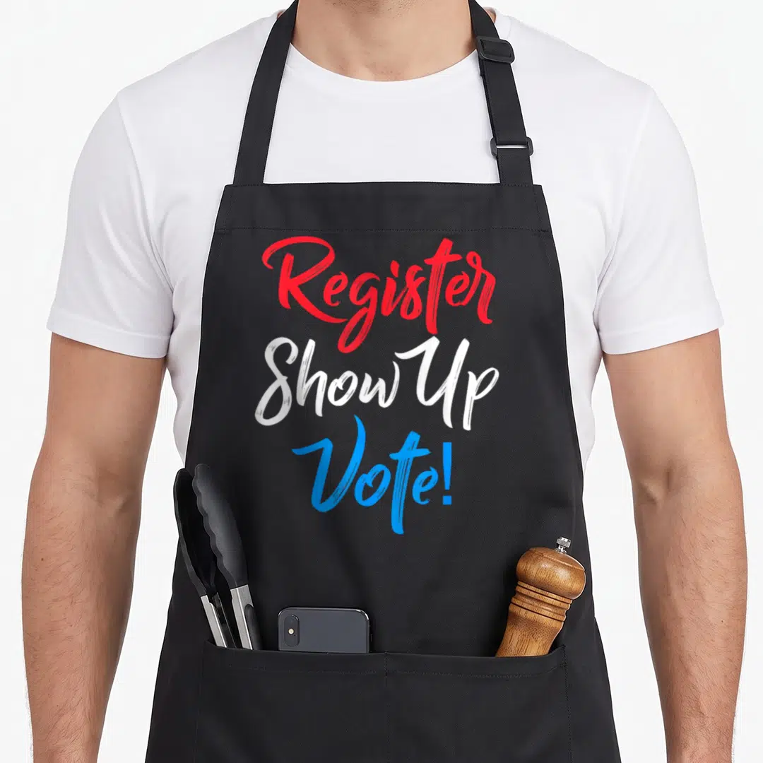 Register vote midterms apron - Stacked red, white, and blue text reading Register Show Up Vote — shown on a black cotton canvas apron against a white background