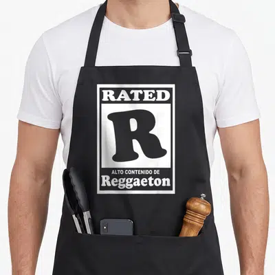 Reggaeton r rated aprons - Grey R movie rating symbol with stacked white text reading Alto Contenido de Reggaeton — shown on a black cotton canvas apron against a white background
