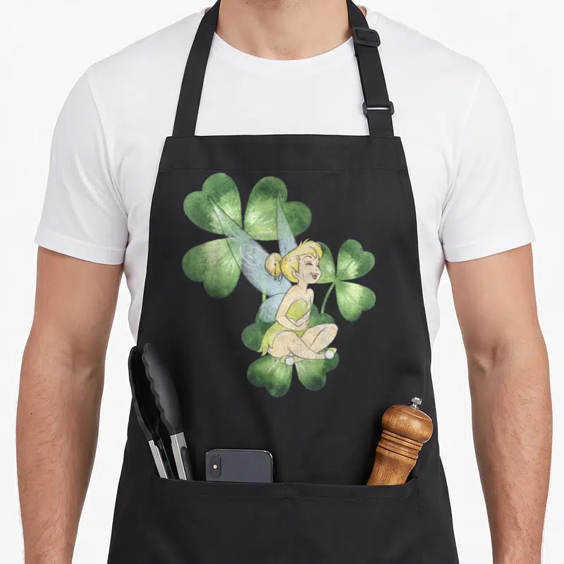 Peter st patrick day aprons - Watercolor fairy sitting on a green shamrock with two larger shamrocks behind in yellow — shown on a black cotton canvas apron against a white background
