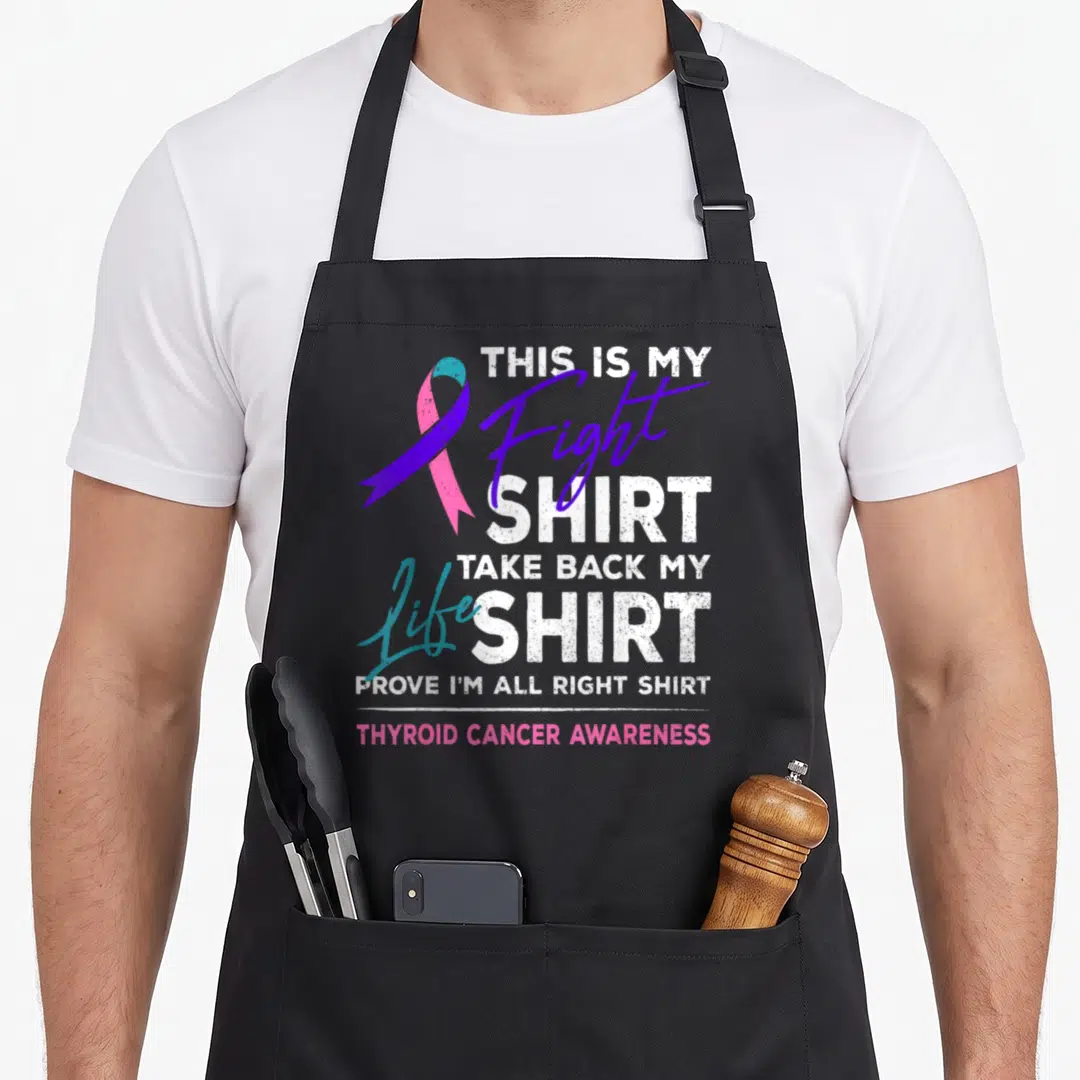 Thyroid ribbon apron - Stacked text reading THIS IS MY Fight SHIRT with purple, teal, pink awareness ribbon — shown on a black cotton canvas apron against a white background