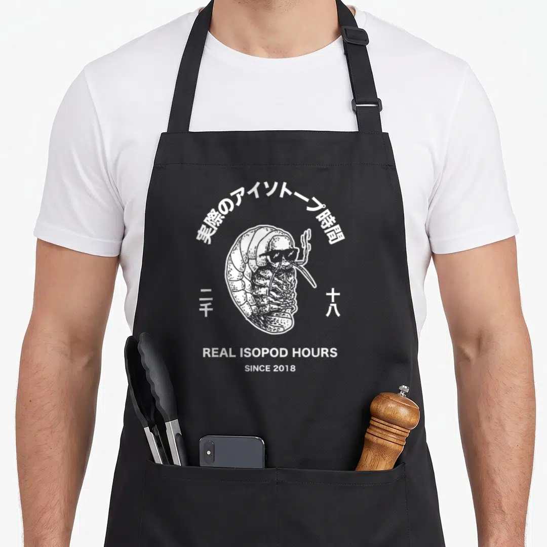 Isopod lover comfort apron - White line art isopod with sunglasses, Japanese text, and Real Isopod Hours stacked below — shown on a black cotton canvas apron against a white background