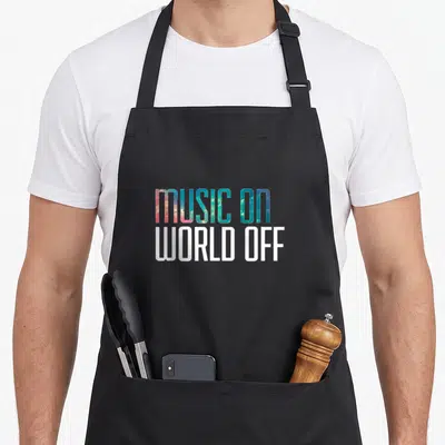 Djs music lovers apron - MUSIC ON WORLD OFF text in blue pink and white stacked typography — shown on a black cotton canvas apron against a white background