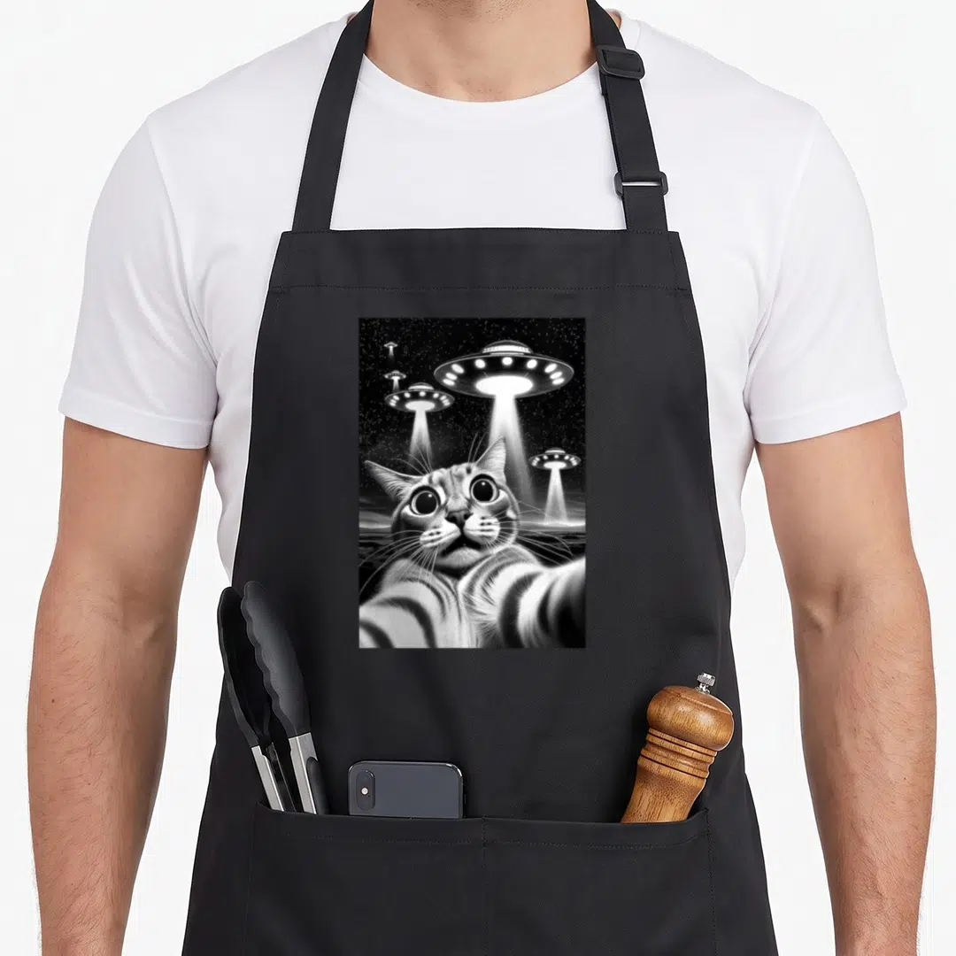 Ufo funny cat apron - Realistic cat selfie with four UFOs beaming light in a starry night sky — shown on a black cotton canvas apron against a white background