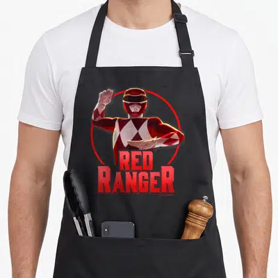 Action rangers apron - Realistic Red Ranger in karate pose inside red circle with bold red text — shown on a black cotton canvas apron against a white background