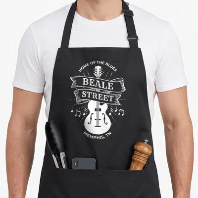 Street memphis apron - White guitar with Beale Street ribbon and Home of the Blues text — shown on a black cotton canvas apron against a white background
