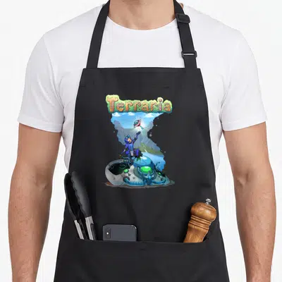 Terraria car apron - Character on crashed spaceship reaching for glowing UFO key under arched Terraria logo — shown on a black cotton canvas apron against a white background