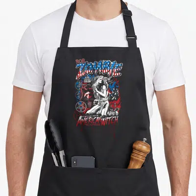 Zombie witch apron - Distressed American flag lettering surrounds a white witch drawing with skulls and pentagrams — shown on a black cotton canvas apron against a white background