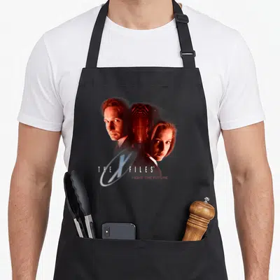 Mulder 90s apron - THE X FILES and FIGHT THE FUTURE text with two people and glowing ring — shown on a black cotton canvas apron against a white background
