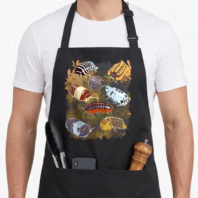 Isopod collection apron - Eight cartoon isopods in orange, brown, blue, red, and purple on autumn leaf background — shown on a black cotton canvas apron against a white background