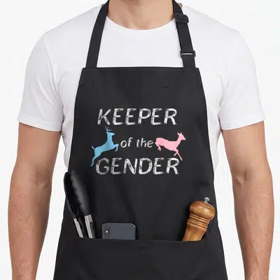 Cute apron or apron - White text KEEPER of the GENDER flanked by jumping blue buck and pink doe silhouettes — shown on a black cotton canvas apron against a white background