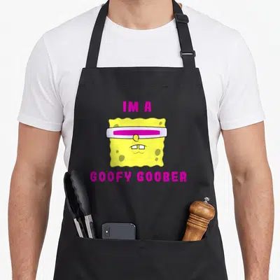Goober general apron - SpongeBob head with white and magenta visor, yellow sponge texture, magenta IM A GOOFY GOOBER — shown on a black cotton canvas apron against a white background