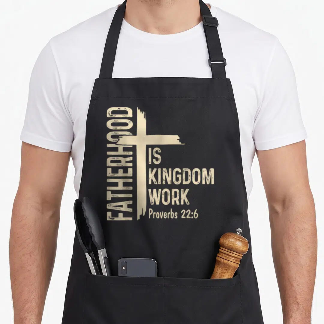 Fatherhood funny christian aprons - Beige distressed cross with vertical Fatherhood text and Proverbs 22:6 stacked — shown on a black cotton canvas apron against a white background