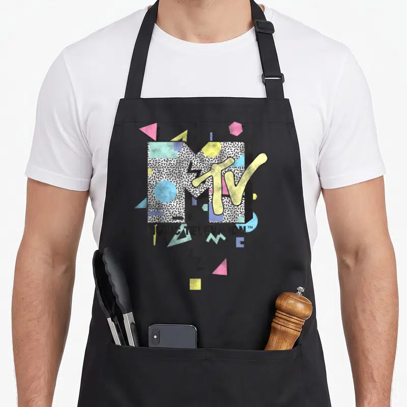 Mtv novelty apron - Retro MTV logo with MUSIC TELEVISION text and geometric shapes in black white yellow pink blue — shown on a black cotton canvas apron against a white background