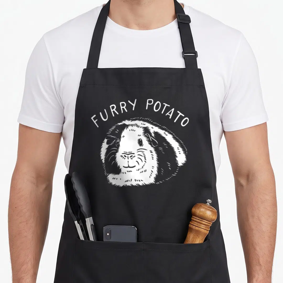 Cavy guinea lover apron - White line art of a guinea pig with arched FURRY POTATO text above it — shown on a black cotton canvas apron against a white background