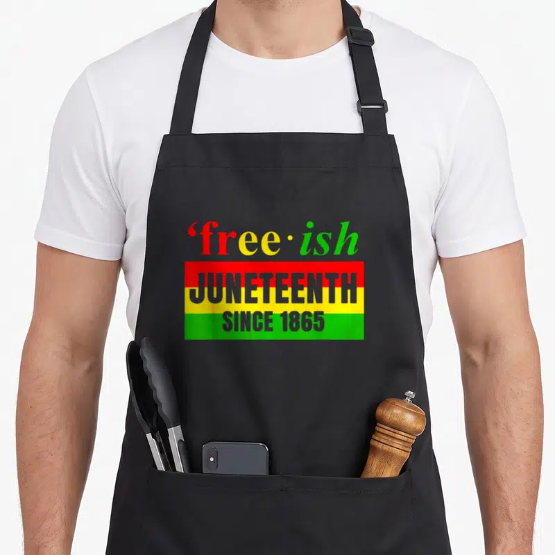 Freedom african american aprons - free-ish text above red yellow green flag with Juneteenth Since 1865 lettering — shown on a black cotton canvas apron against a white background
