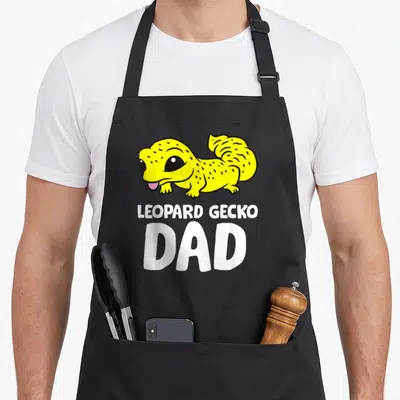 Gecko reptile leopard apron - Cartoon yellow leopard gecko above white text LEOPARD GECKO DAD — shown on a black cotton canvas apron against a white background